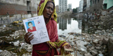 A mourner holds up a portrait of her missing relative following the 2013 collapse of the Rana Plaza garment building near Dhaka, Bangladesh © Getty Images