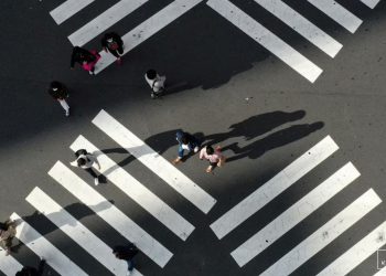 People cross a street in front of Shinjuku station, a normally crowded street during the weekend.