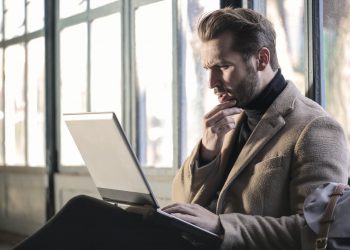 Man holding his chin facing laptop